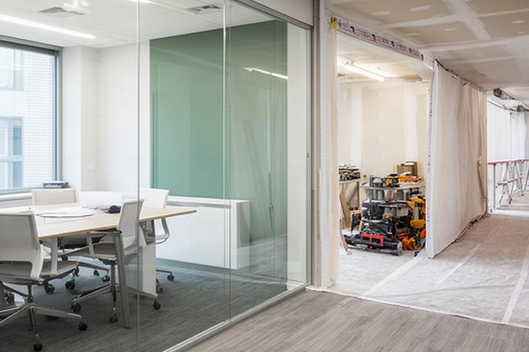 Professional office renovation with a completed glazed meeting room and adjacent active work zone separated for phased construction